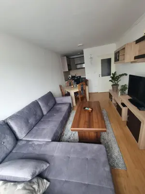 a living room with a gray couch and a wooden table at CityLux Doboj in Doboj