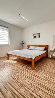 a large bed in a room with a wooden floor at MG in Žepče