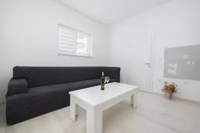 a living room with a black couch and a white table at Apartman BARIŠIĆ 1 in Kupres