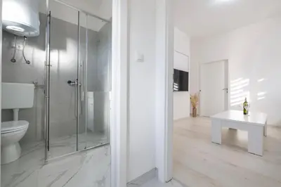 a white bathroom with a toilet and a glass shower at Apartman BARIŠIĆ 1 in Kupres
