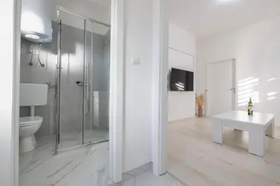 a bathroom with a shower and a toilet and a table at Apartman BARIŠIĆ 1 in Kupres