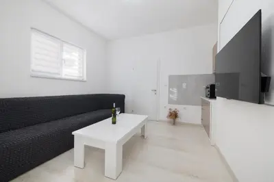 a living room with a black couch and a white table at Apartman BARIŠIĆ 1 in Kupres