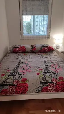 a bed with a floral bedspread with two towers at Apartmani Elix in Banja Luka