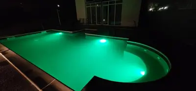 a swimming pool with green illumination at night at Vikendica OM relax in Prijedor