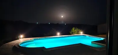 a blue swimming pool at night with lights at Vikendica OM relax in Prijedor