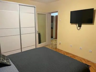 a bedroom with a bed and a flat screen tv at Apartman 2E in Tuzla