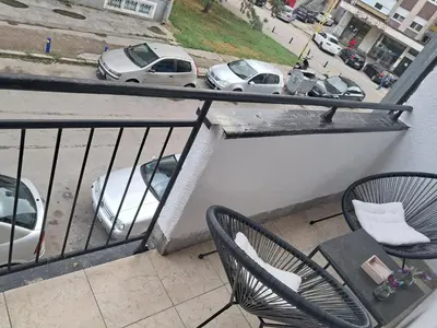 a balcony with two chairs and a table and cars at Apartman 2E in Tuzla