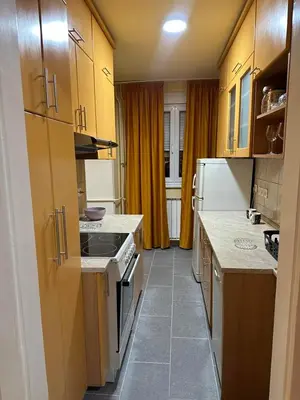 a kitchen with yellow cabinets and a stove top oven at Apartman 2E in Tuzla