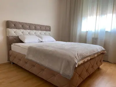a bed with a large headboard and a window at Apartman MARIJA in Bosanski Šamac