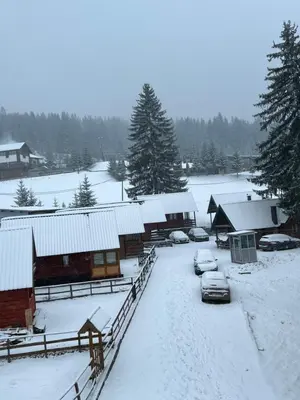 a snow covered yard with parked cars and buildings at Apartman Vlašić Hary in Vlasic
