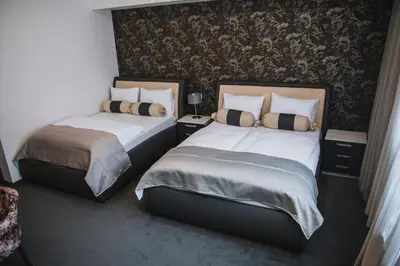 two beds in a hotel room with a wall at Hotel Bacchus in Livno