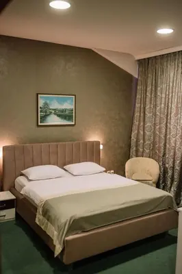a bedroom with a large bed and a chair at Hotel Bacchus in Livno