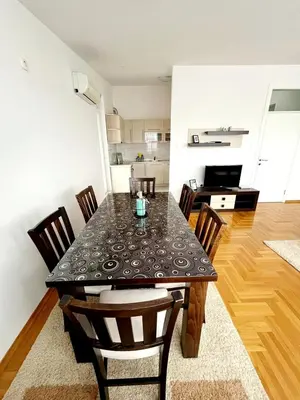 a dining room table with chairs and a kitchen at Apartments Family House in Banja Luka