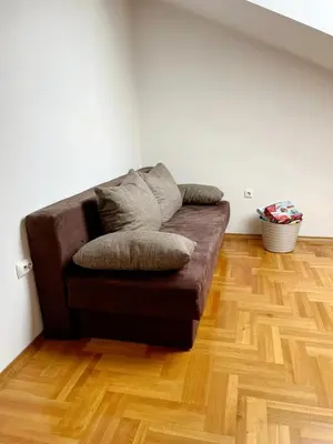 a brown couch in a room with a wooden floor at Apartments Family House in Banja Luka