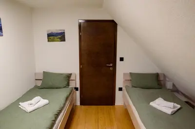 two twin beds in a room with a door at Strane in Tomislavgrad
