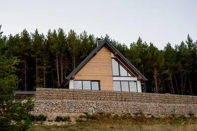 a house behind a stone wall with trees in the background at Strane in Tomislavgrad