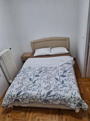a bedroom with a bed with a blue and white comforter at centar apartment in Banja Luka