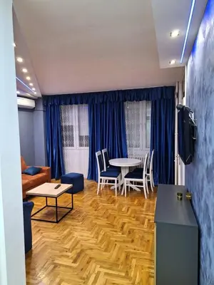 a living room with blue curtains and a table and chairs at centar apartment in Banja Luka