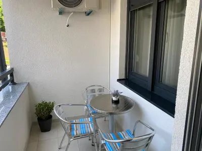 a small table and chairs on a balcony at Zeus apartman in Hiseti