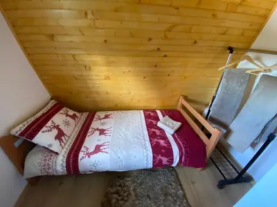 a bed in a room with a wooden wall at Apartmani Snježna Kraljica Vlašić 1 in Vlasic