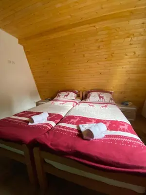 a bed with red and white sheets and pillows at Apartmani Snježna Kraljica Vlašić 1 in Vlasic