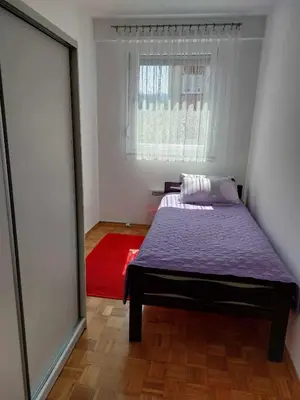 a bedroom with a bed and a window and a red rug at Apartman OMANOVIĆ in Bihać
