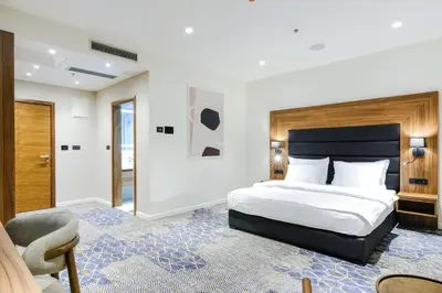 a bedroom with a king sized bed and a chair at Hotel Vema in Visoko