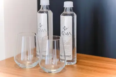 three empty wine glasses and bottles on a wooden table at Hotel Vema in Visoko