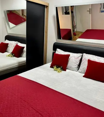 a bedroom with two beds with red pillows and a mirror at Stan na dan Kozarska Dubica in Bosanska Dubica