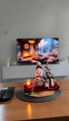 a table with a candle and a snowman figurine next to a remote control at Stan na dan Hasanovic in Tuzla