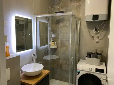 a bathroom with a shower and a sink and a washing machine at Zeus in Hiseti