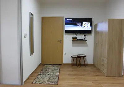 a hallway with a door and a television on a wall at Restart Apartment in Visoko