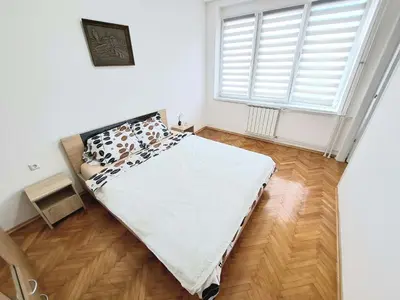 a bedroom with a bed and a large window at Apartman Skver Tuzla in Tuzla