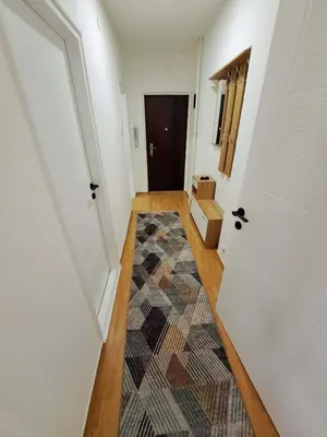 a hallway with a door and a rug at Apartman Skver Tuzla in Tuzla