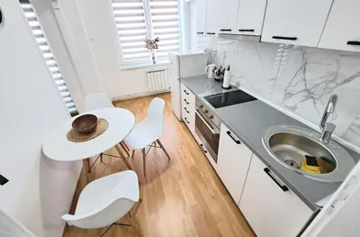 a kitchen with a sink and a table and chairs at Apartman Skver Tuzla in Tuzla