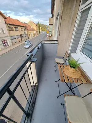 a balcony with a table and chairs and a street at Apartman Skver Tuzla in Tuzla