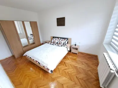 a bedroom with a bed and a wooden floor at Apartman Skver Tuzla in Tuzla
