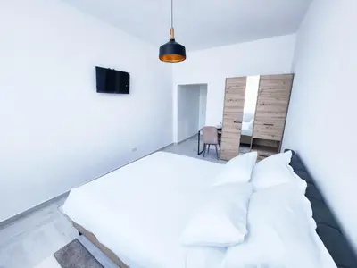 a white bedroom with a bed and a table at Hotel Balon in Velika Kladuša
