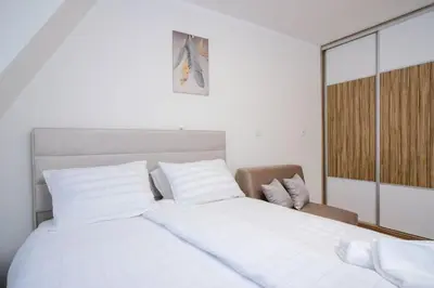 a bedroom with a large white bed and a chair at Lux Sara Apartments in Visoko