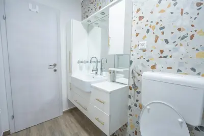 a white bathroom with a toilet and a sink at Calendula apartments in Tuzla