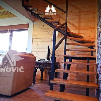 a wooden staircase in a room with a couch and a table at Vikendica Stevanovic in Doboj