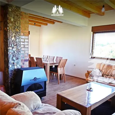 a living room with a fireplace and a table with chairs at Vikendica Stevanovic in Doboj
