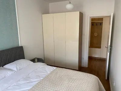 a bedroom with a white bed and a cabinet at Zeus apartman in Banja Luka