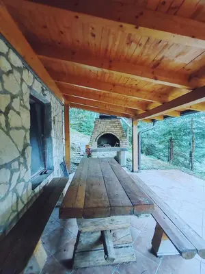 a wooden picnic table on a patio with a stone oven at Apartments Planinski raj in Travnik