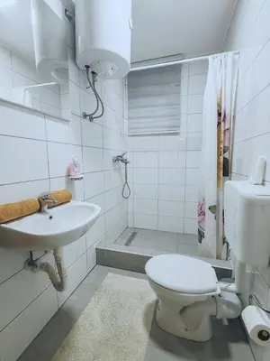 a white bathroom with a toilet and a sink at Apartments Planinski raj in Travnik