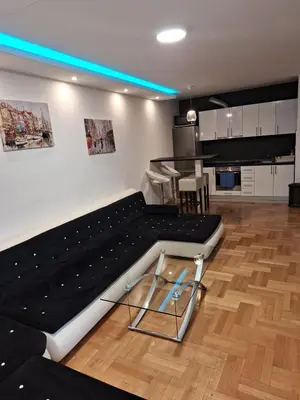 a living room with a large black bed and a kitchen at Luks apartment in Banja Luka
