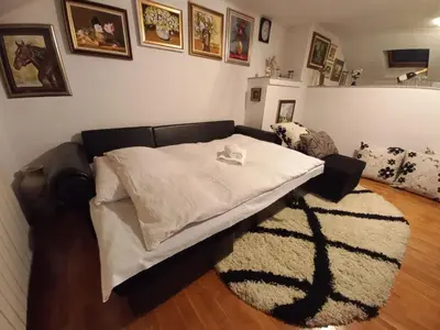 a bed with a white blanket on top of a rug at Apartman Bony M in Kiseljak