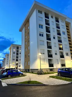 a large white building with cars parked in a parking lot at SunShine Apartman CityBlock in Banja Luka