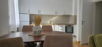 a kitchen with a table and chairs and a kitchen with white cabinets at SunShine Apartman CityBlock in Banja Luka
