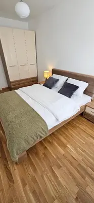 a large bed in a room with a wooden floor at SunShine Apartman CityBlock in Banja Luka